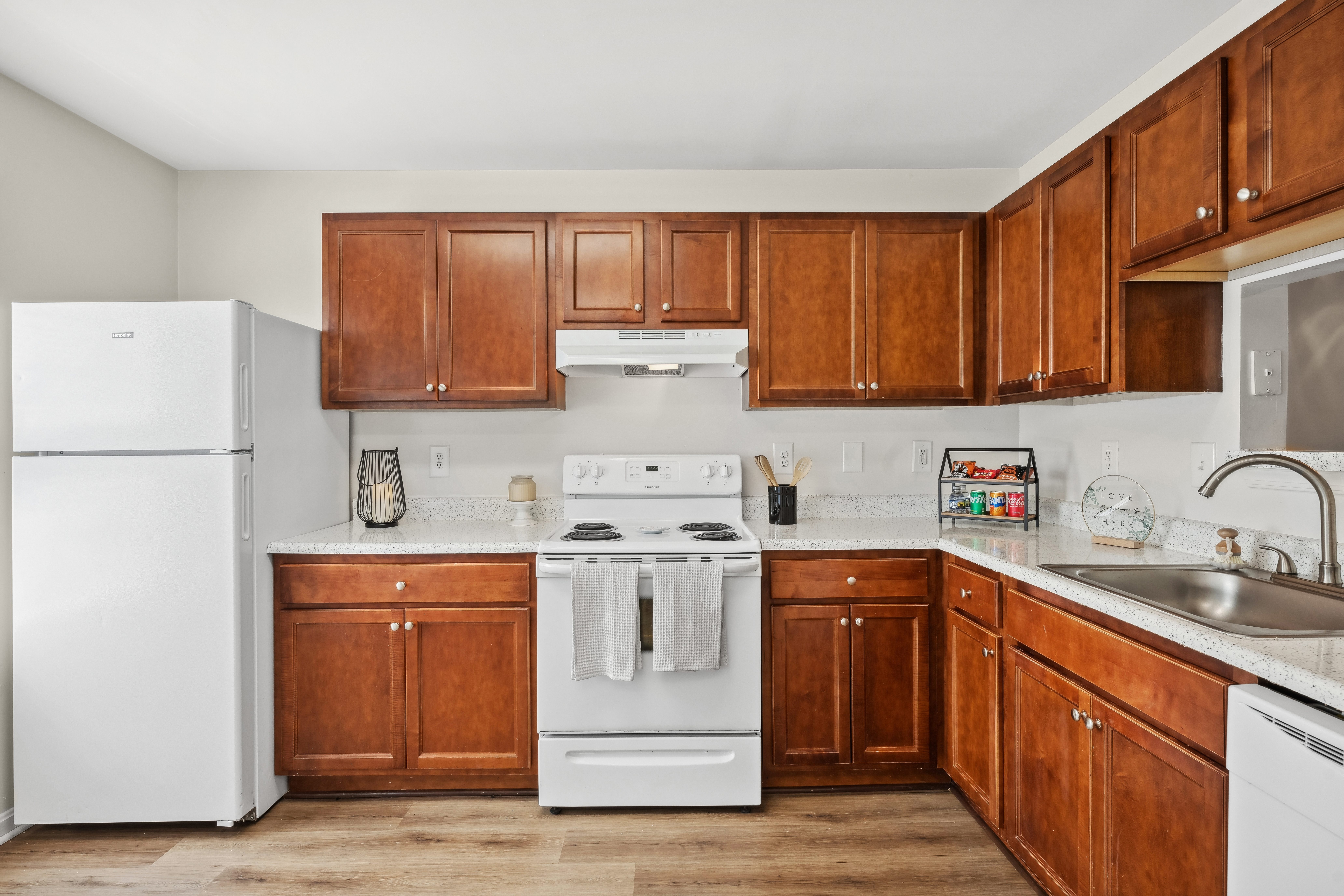 A kitchen with white appliances and wooden cabinets.